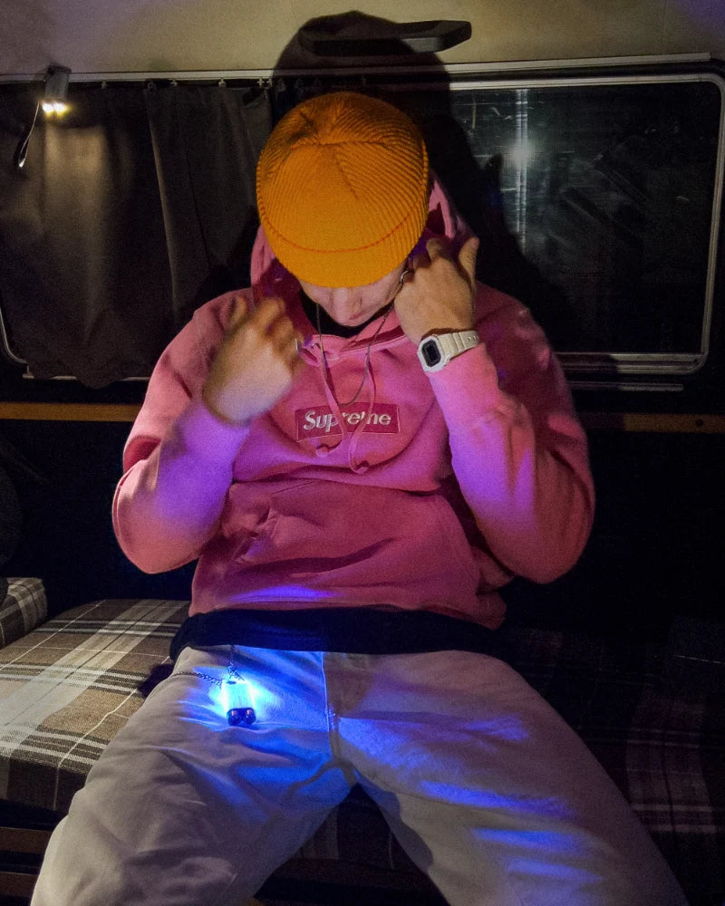 Person sitting in a car at night with a Beaconix B3 Mini glowing blue at the hip